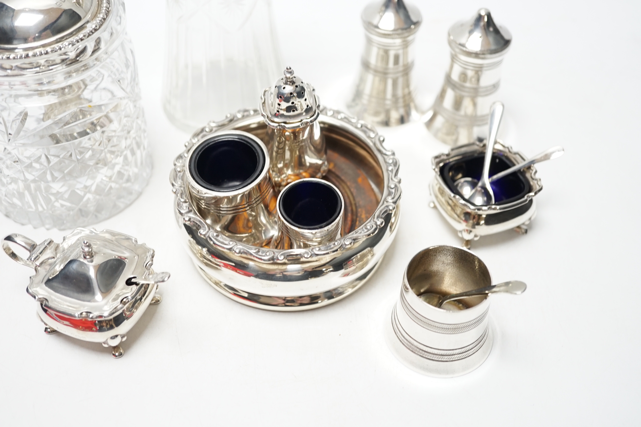 An Edwardian silver wine coaster, William Hutton & Sons, Birmingham, 1903, diameter 10.4cm, a later silver three piece condiment set, a silver mounted glass preserve jar, with a George silver teaspoon and six plated item